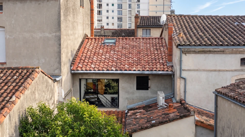 Vue aérienne d'un ensemble de toitures en tuiles canal terre cuite, dans un quartier urbain dense